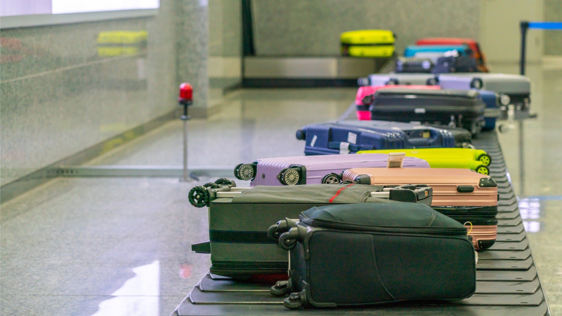 This image shows a dozen suitcases on a conveyor belt at an airport. 