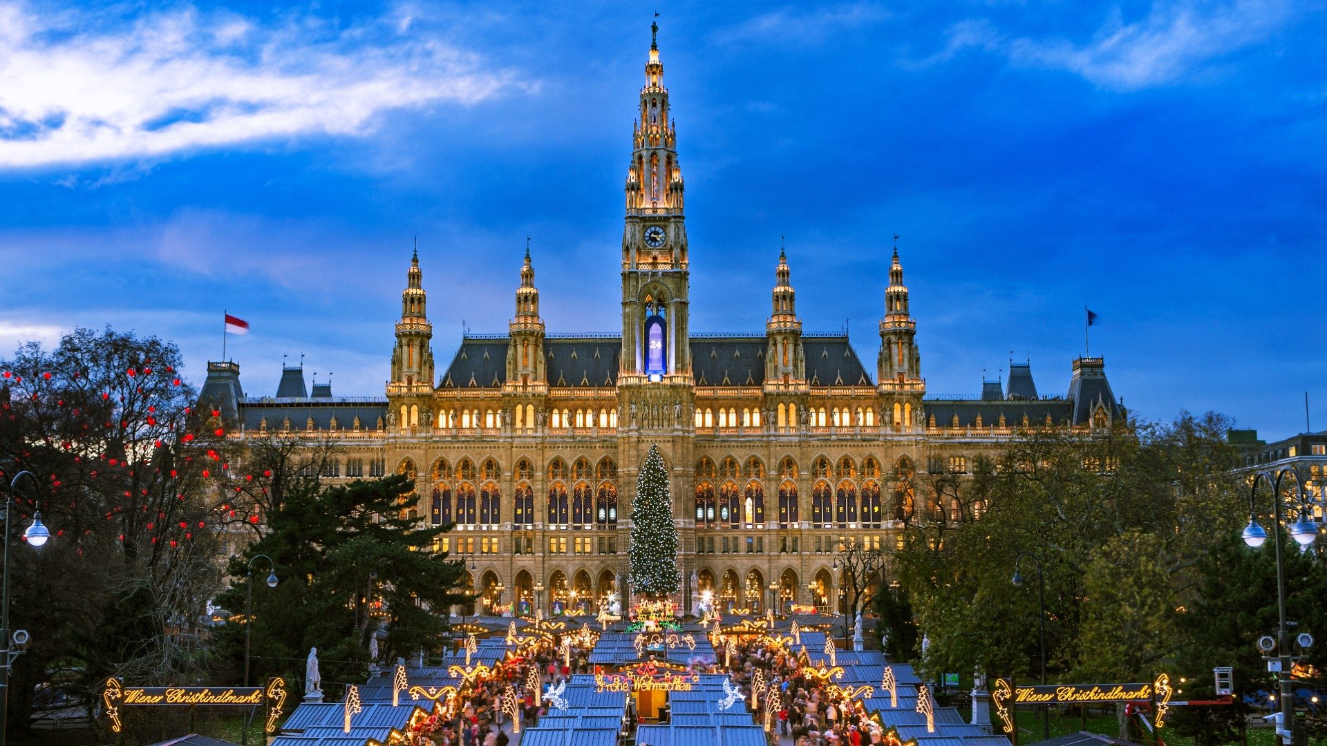 This is a panoramic view of the City Hall and the Christmas Market that spreads in front of it. The City Hall is festively illuminated 