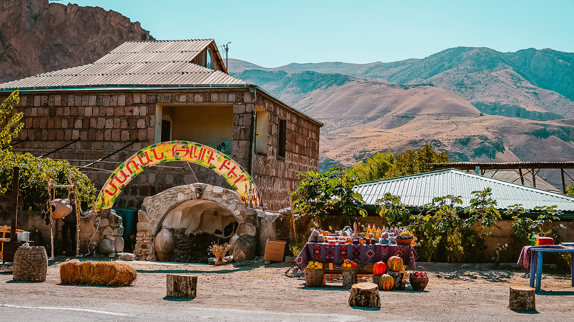 View of a Winery in Areni, Armenia, with mountains in the background and stalls with homemade products in the front.