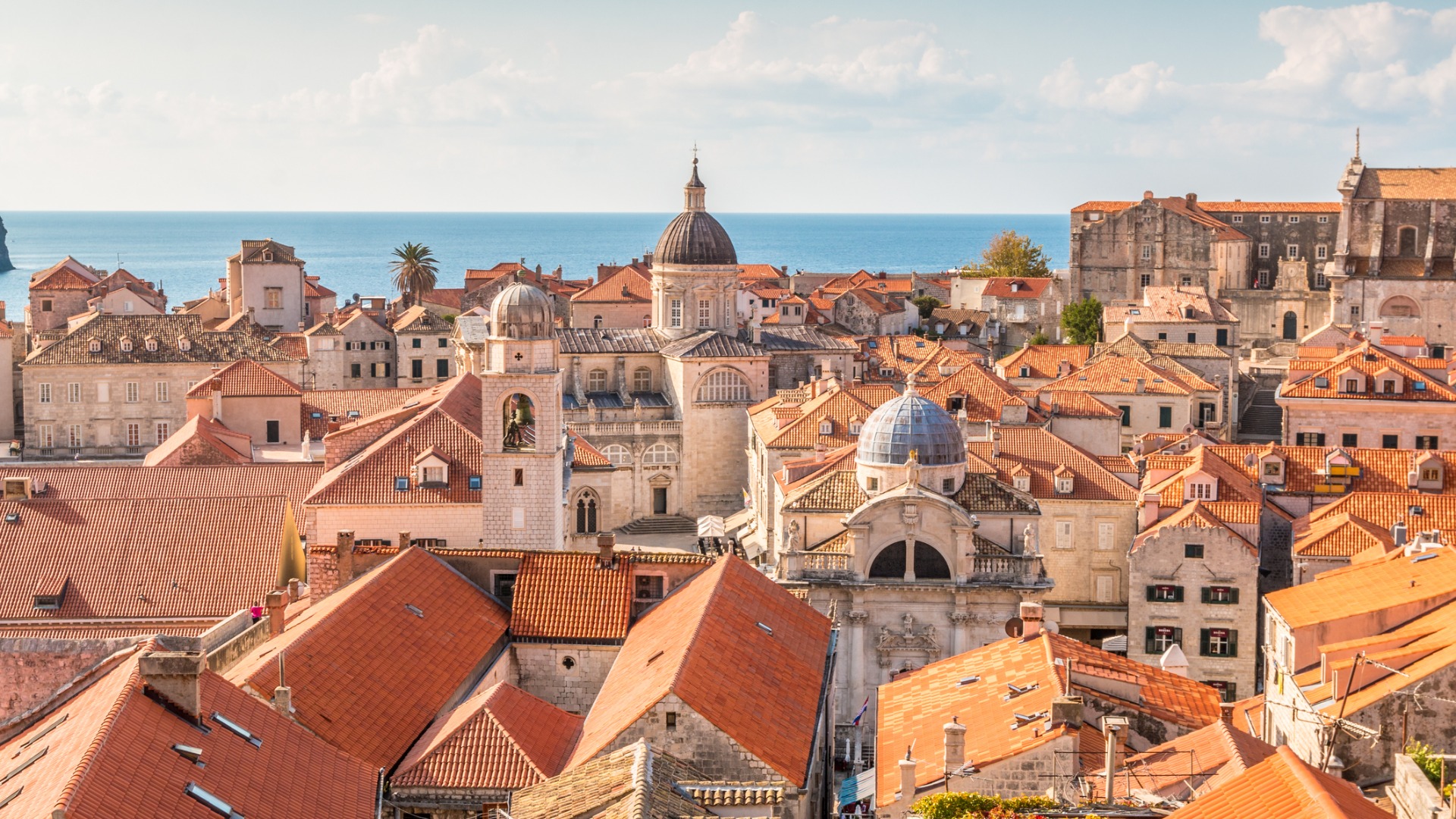 Această imagine arată acoperișurile roșii ale Dubrovnikului cu marea în fundal.