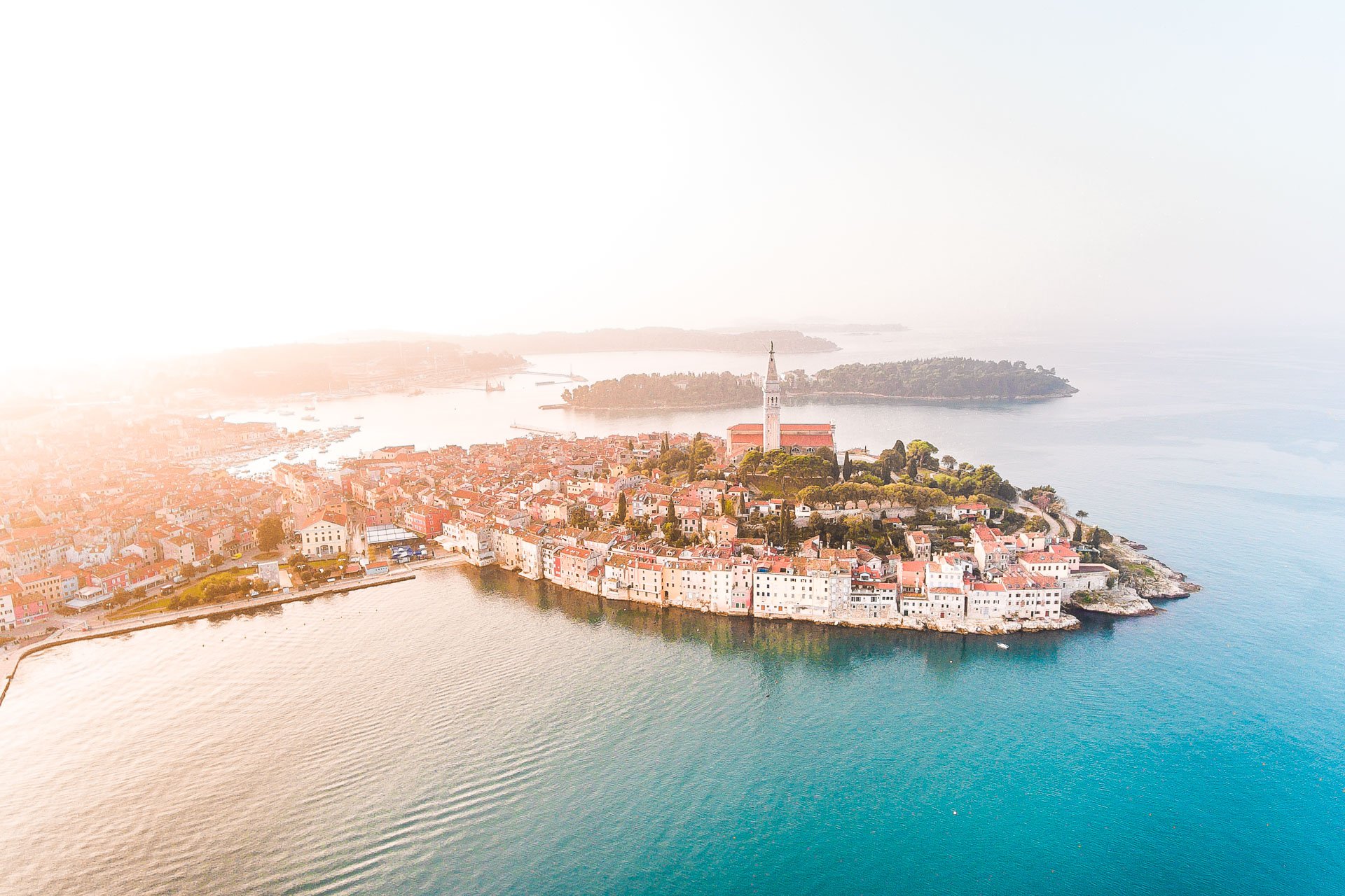 This is a panoramic drone shot of Rovinj at sunset. 