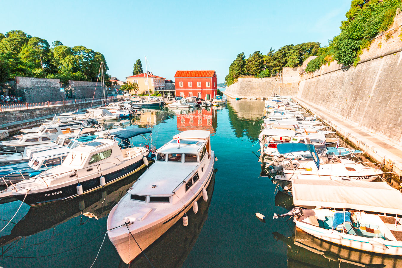 This image shows fishing boats in a canal lined by city walls. 