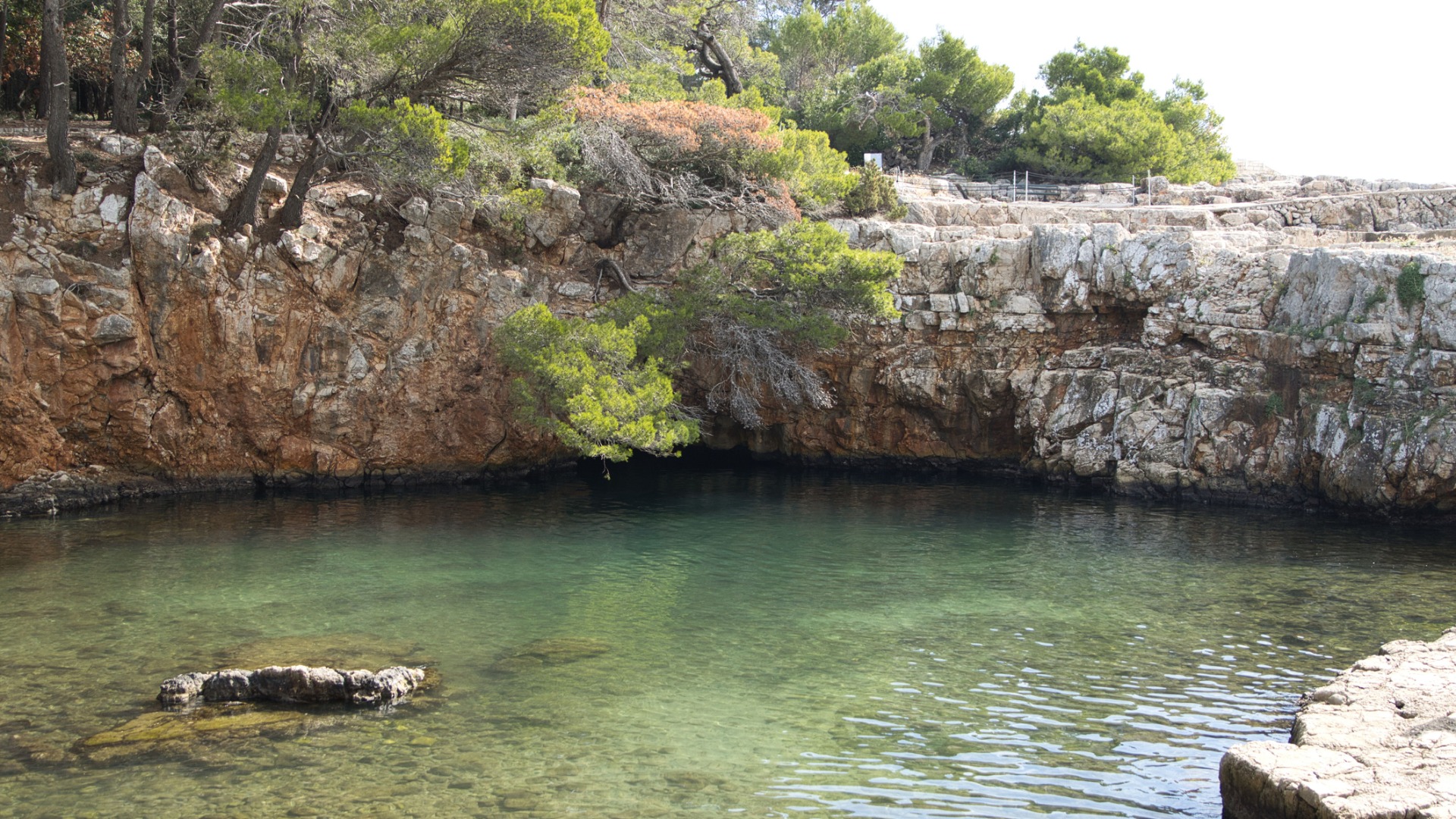 This is an image of the Dead Sea in Lokrum with its tranquil waters amidst tall rocks. 