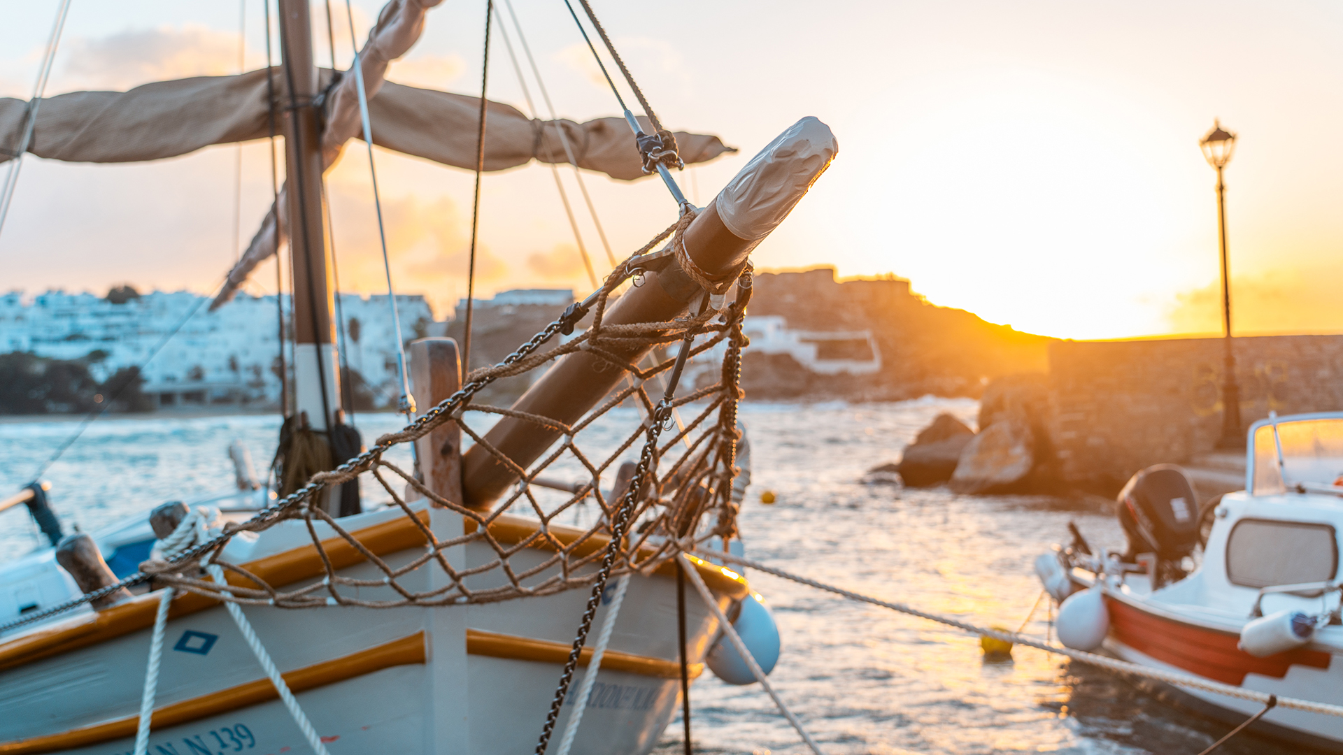 This image shows a traditional Greek wooden boat. In the background, Naoussa in Paros is washed in the sunset light.