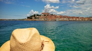 This image shows a straw hat in the foreground and Rovinj in the background.