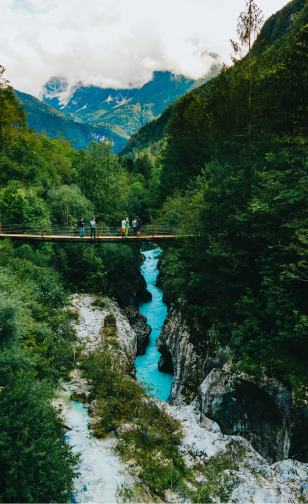 The Soča River Valley in Slovenia, a bright turquoise river flanked by steep cliffs, with mountains in the background.