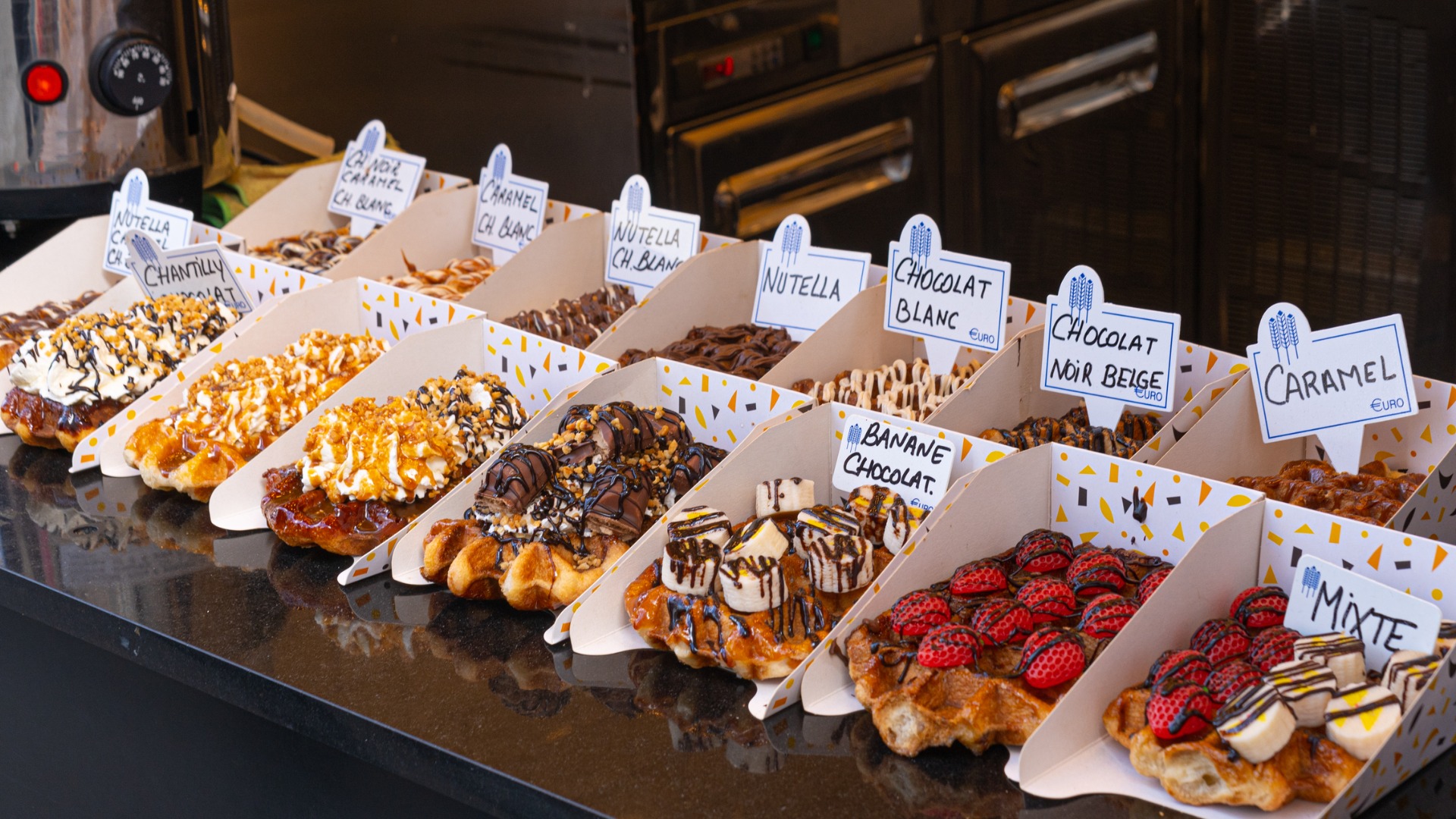 This image shows a display of several Belgian waffles with various colorful toppings. 