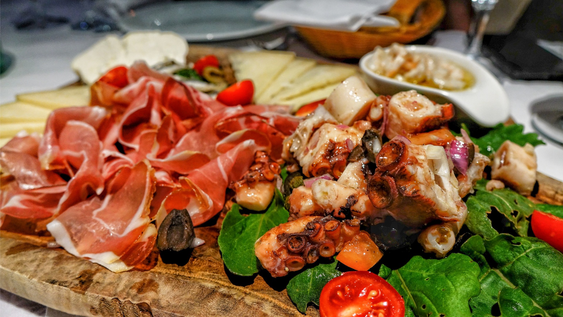 This image shows a platter filled with prsut, octopus, and cheese.