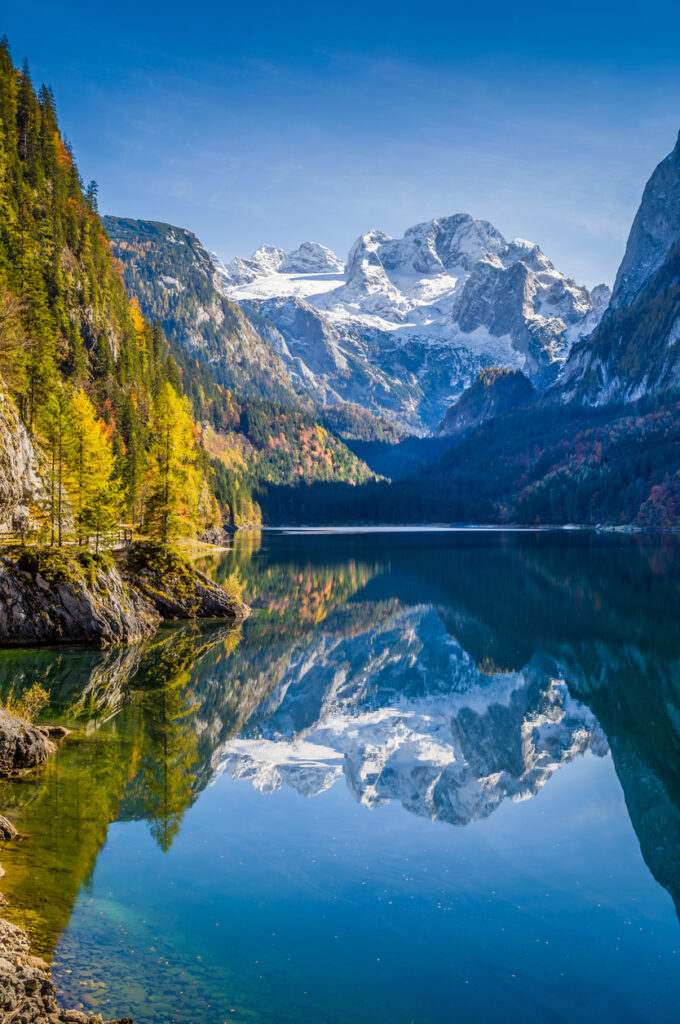 Beautiful view of idyllic colorful autumn scenery with Dachstein mountain summit reflecting in crystal clear Gosausee mountain lake in fall, Salzkammergut region, Upper Austria, Austria