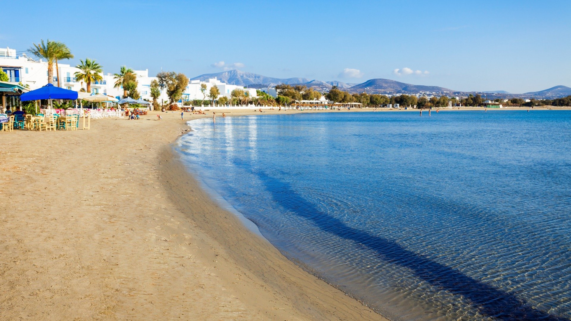 This is a panoramic view of the long sandy beach of Agios Georgios, lined with traditional restaurants right by the water. 
