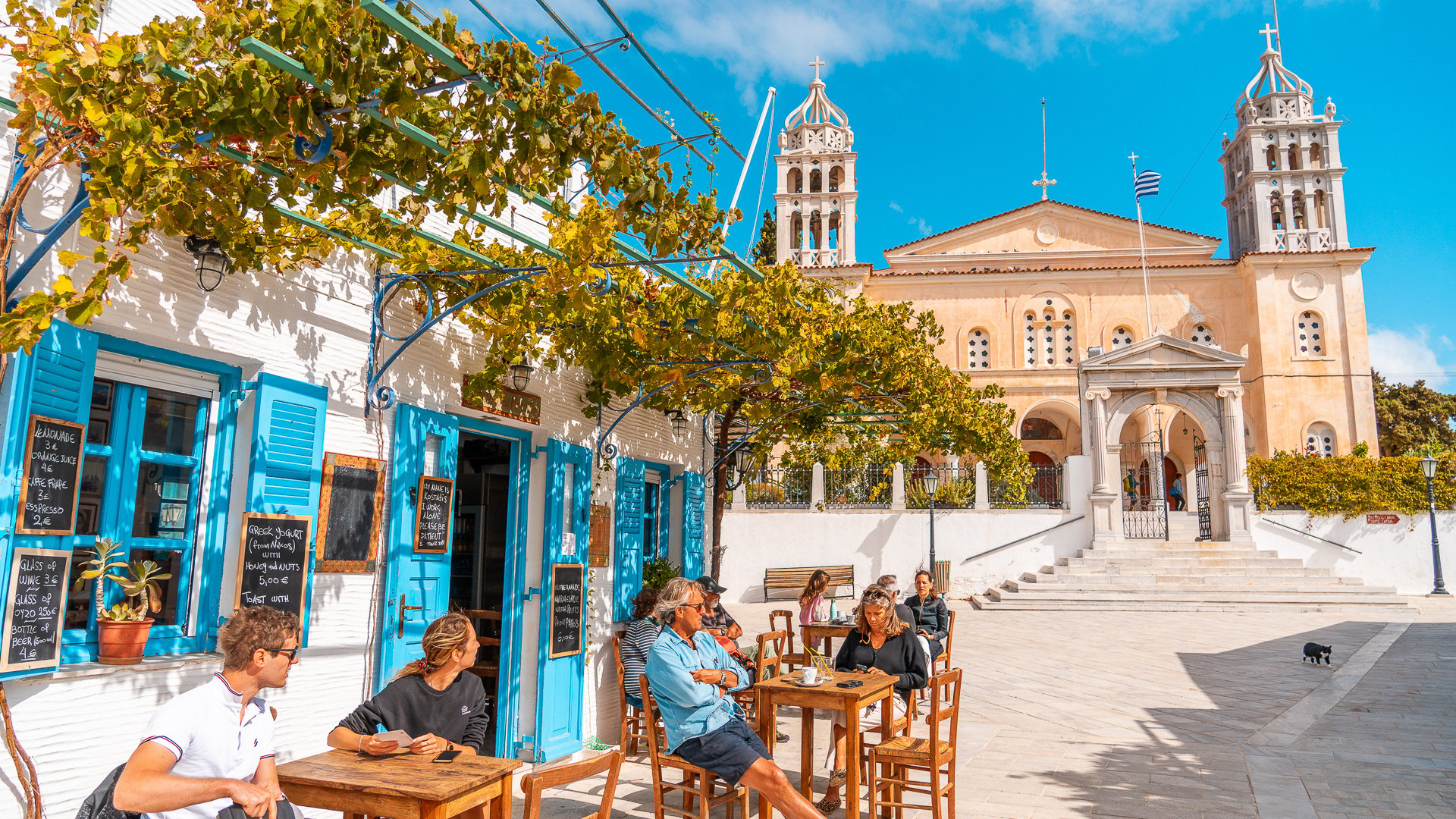 This image shows people sitting at traditional café in Lefkes. The village's large church dominates the background. 