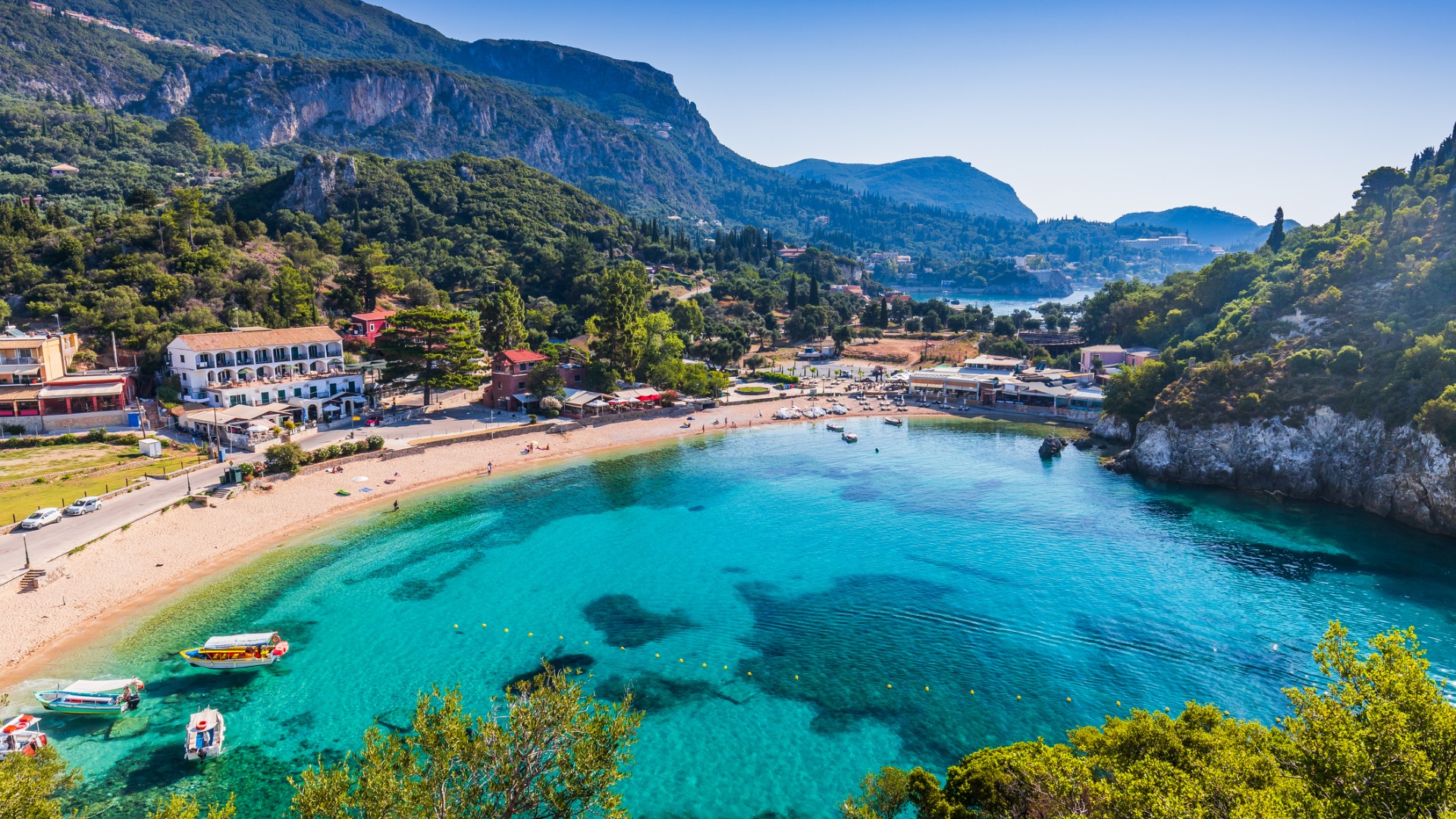 A panoramic view of Paleokastritsa Bay with its turquoise waters, surrounded by a lush forest. 