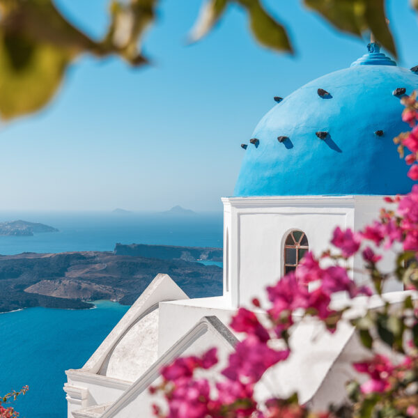 This image shows a blue-domed church in the foreground and the Santorini Volcano in the background.