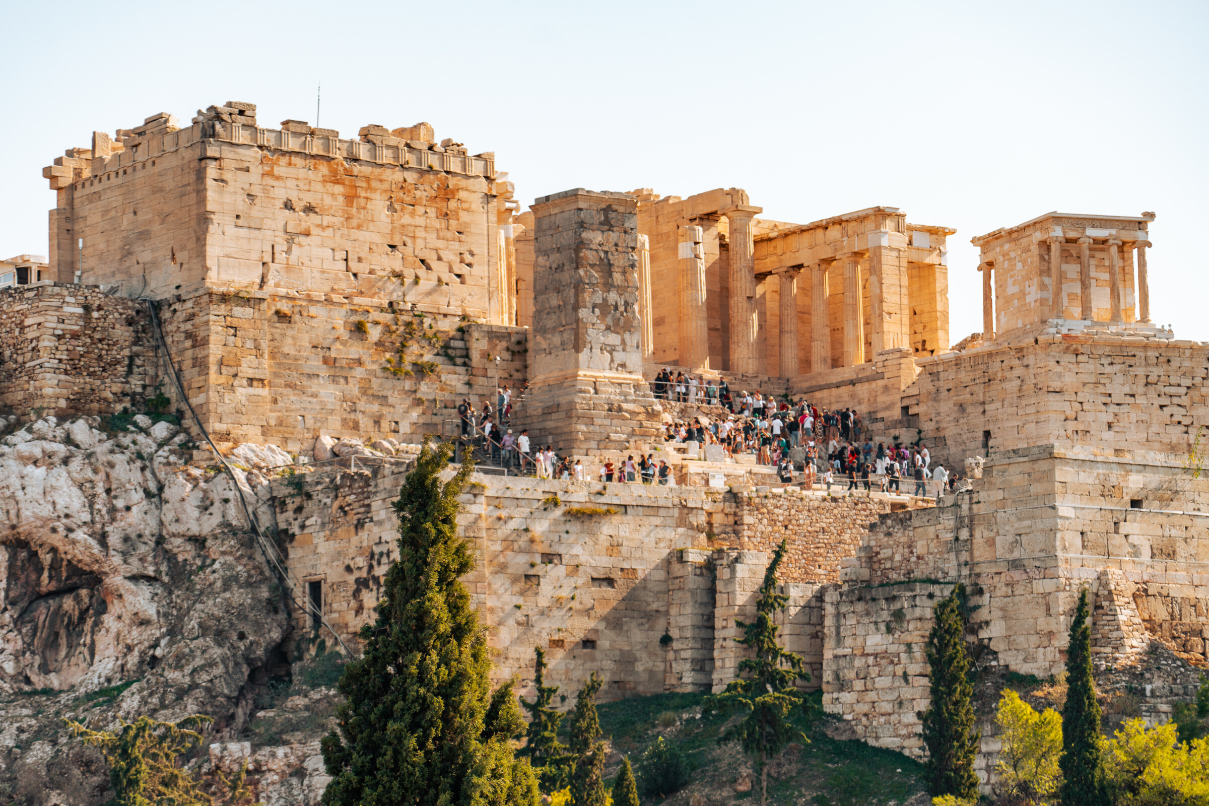 This is a panoramic view of the Acropolis in Athens with several visitors. 