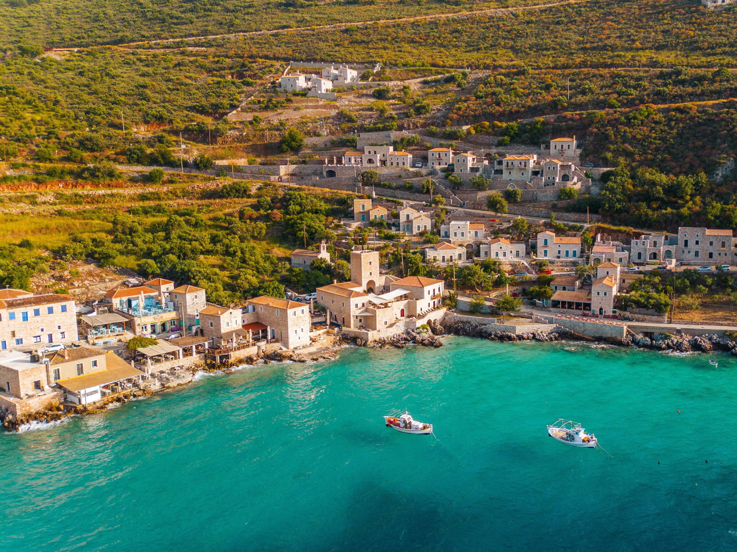 This is a panoramic drone shot of the seaside village of Limeni in the Peloponnese, a Greek region you should consider when planning a trip to Italy and Greece.