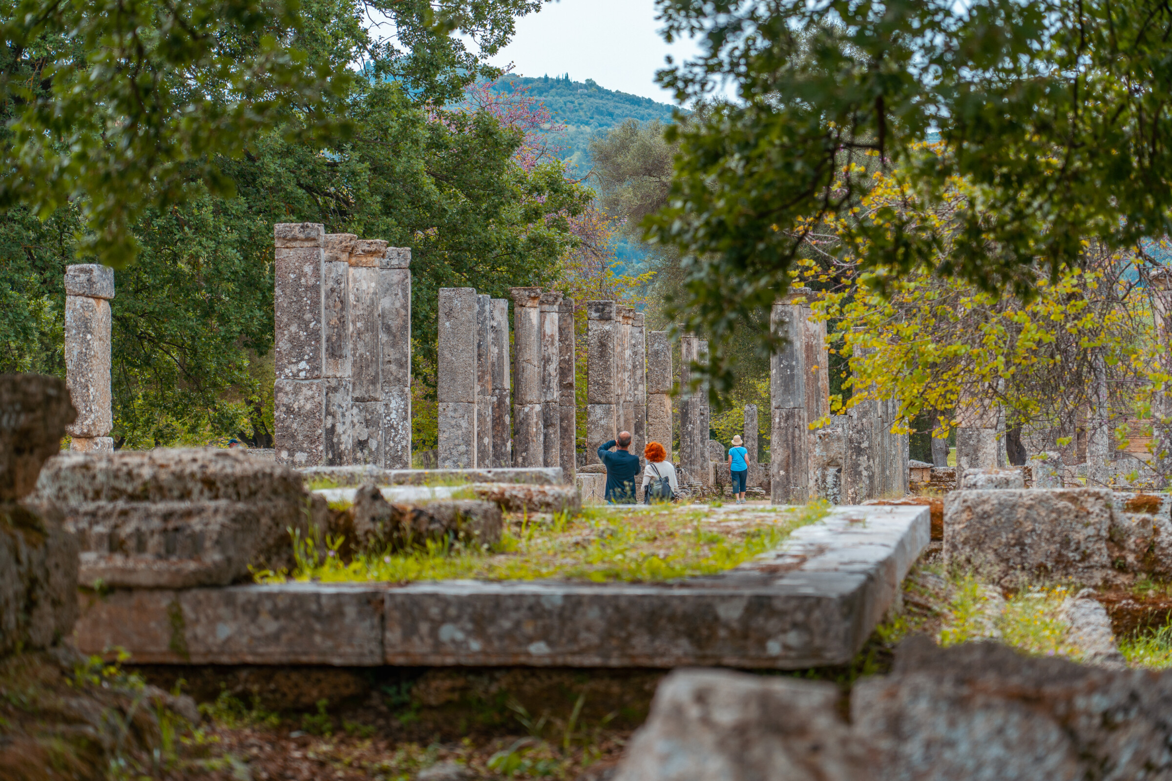 This image shows ancient columns and people walking among them. 