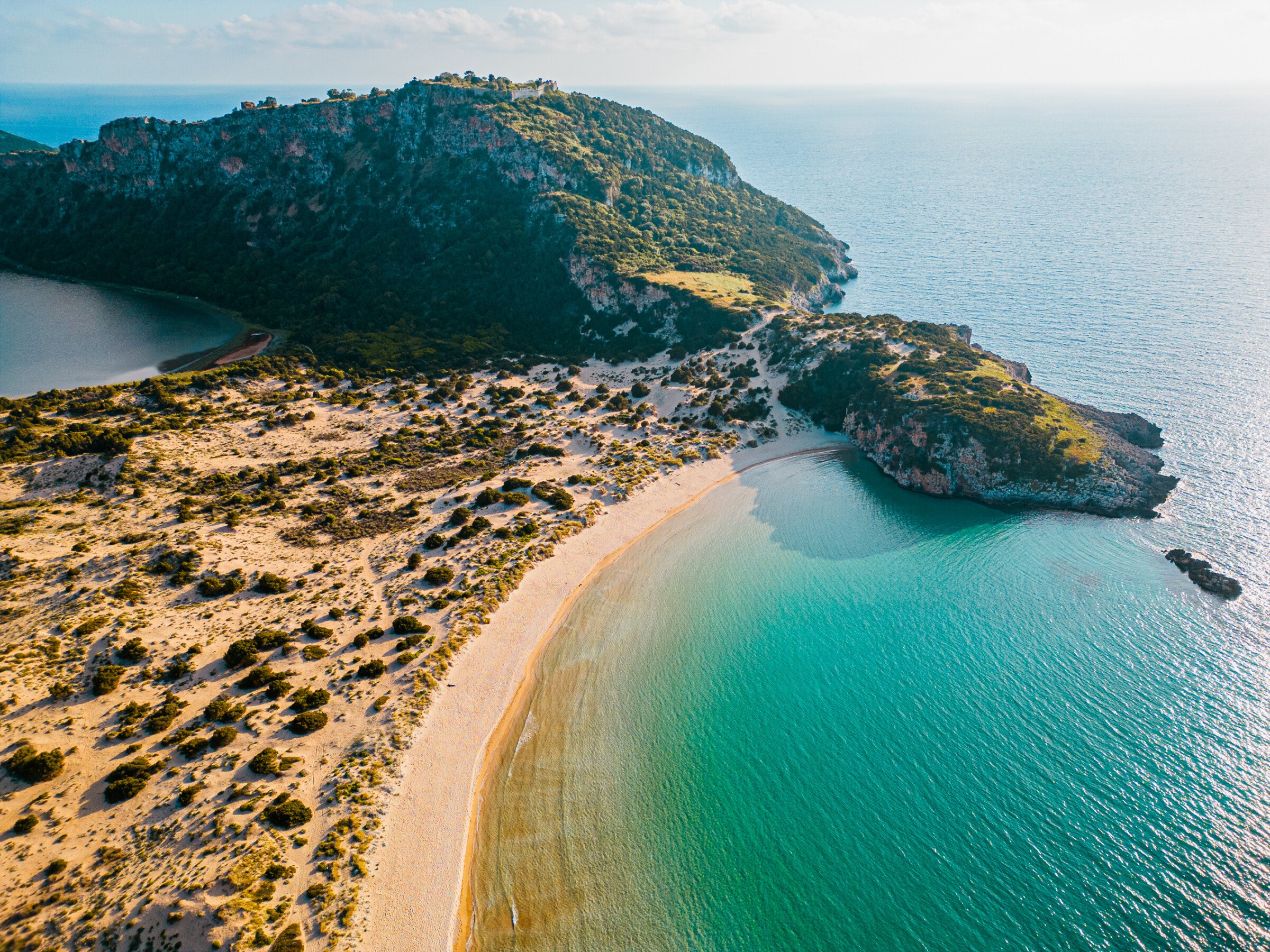 This is a drone shot of Voidokilia Beach with its shallow turquoise waters. 