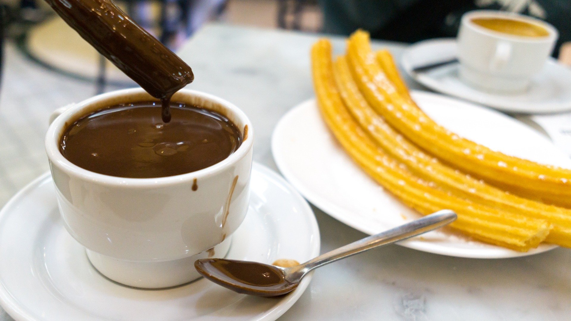 This image shows a cup of thich hot chocolate and churros. 