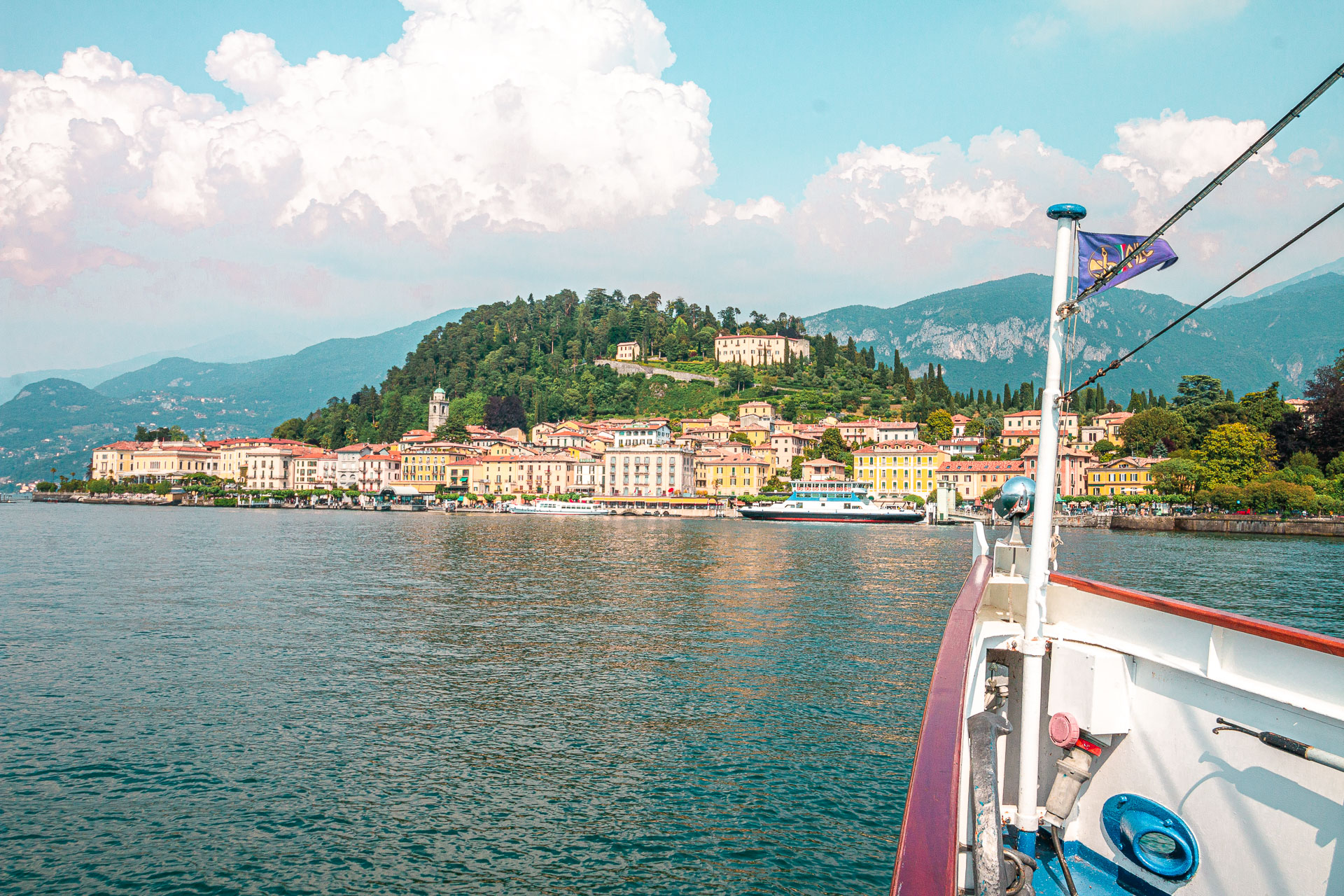 This image shows a boat approaching a small quaint town on the shore of Lake Como, one of the best places to visit in Italy. 