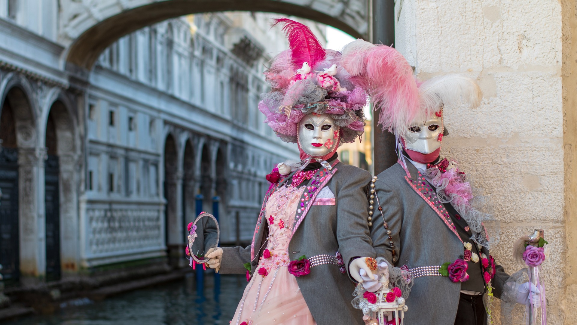 Two models disguised in Venetian Carnival costumes are posing near the Bridge of Sighs.