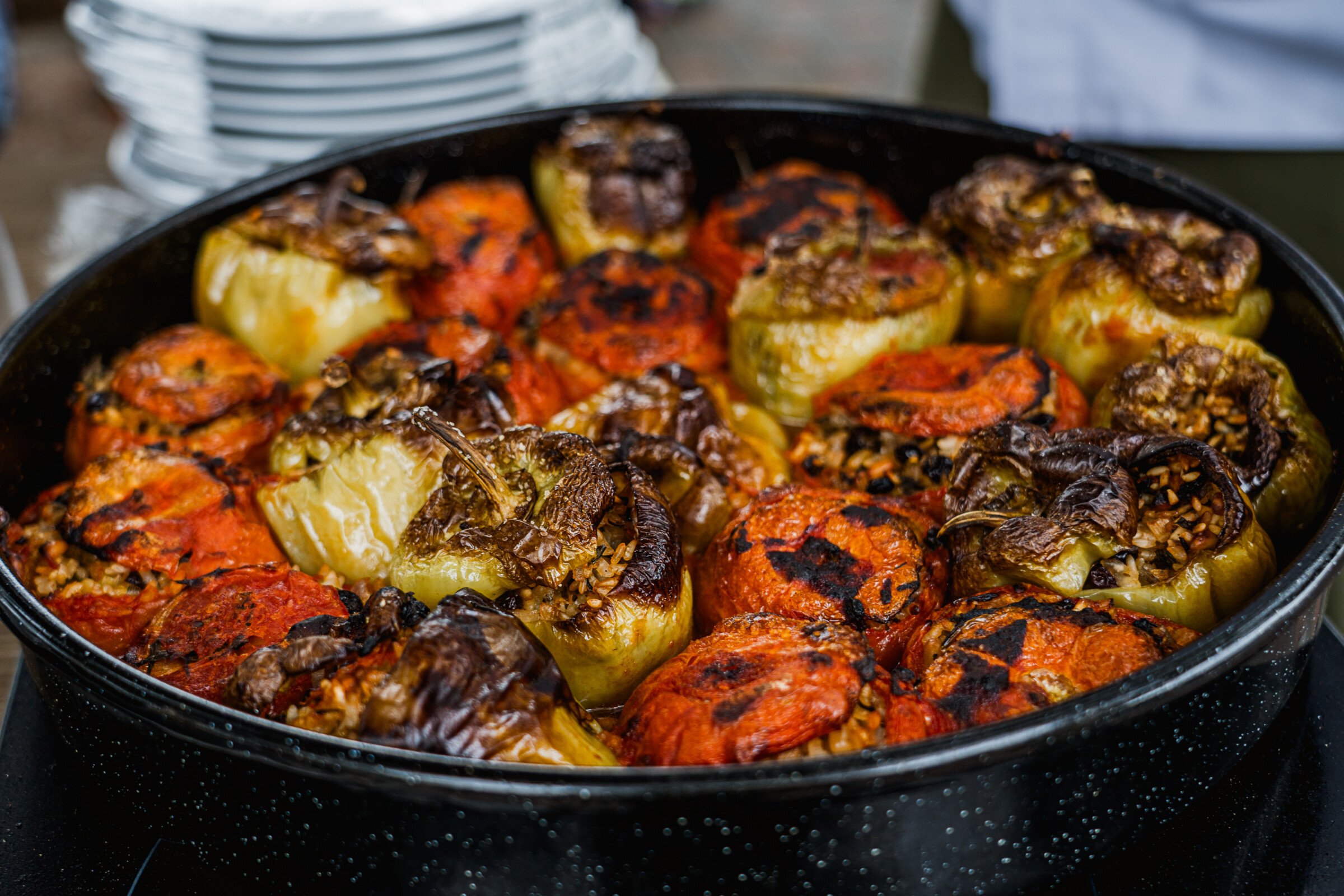 A round baking pan filled with stuffed tomatoes and green bell peppers. 