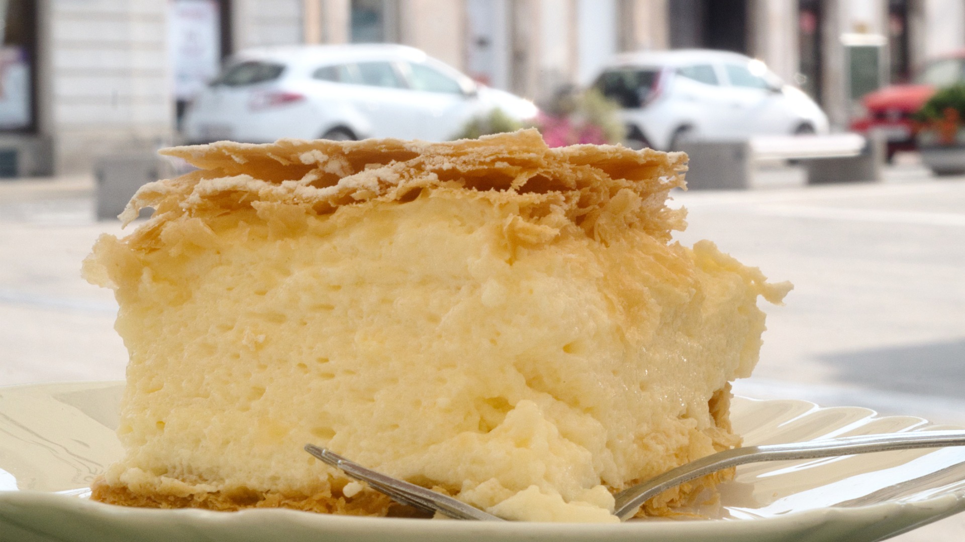 This is a close up of a piece of Kremsnita cake at an outdoor cafe. 