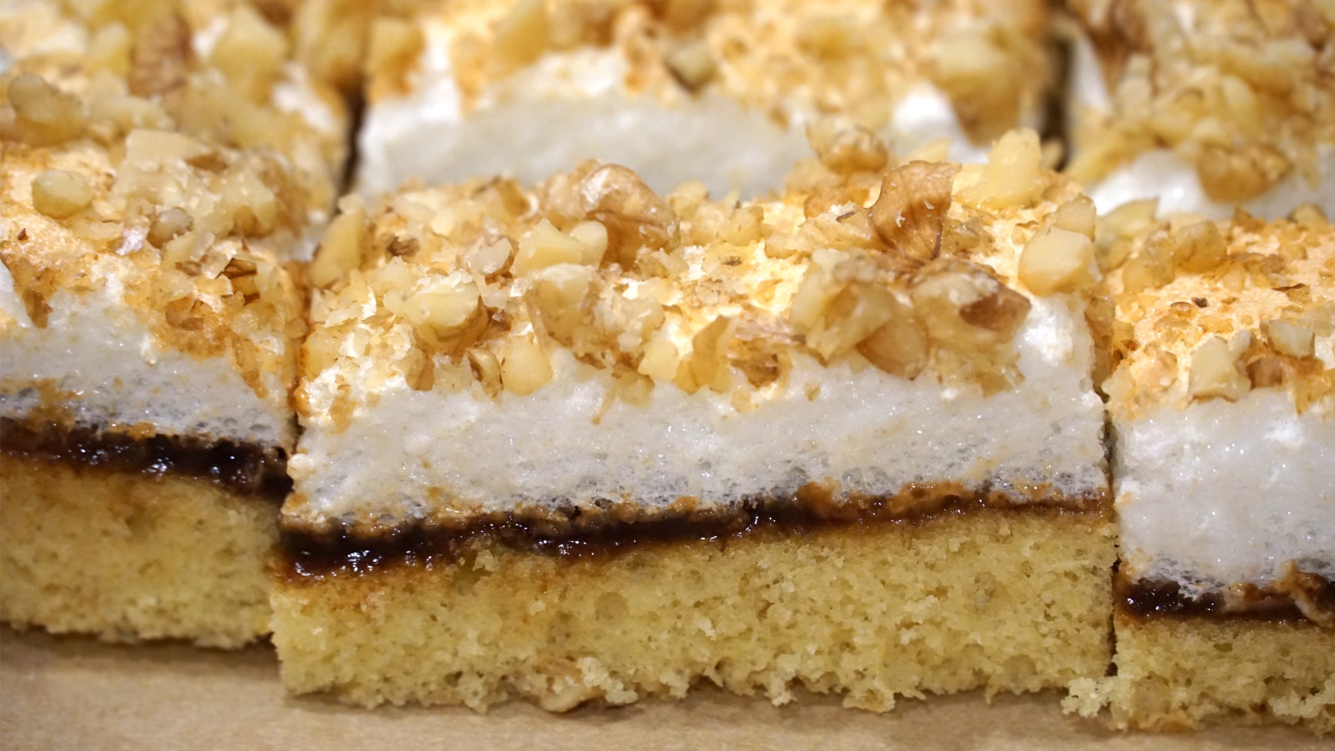 A close up of pieces of layered cake topped with chopped walnuts. 