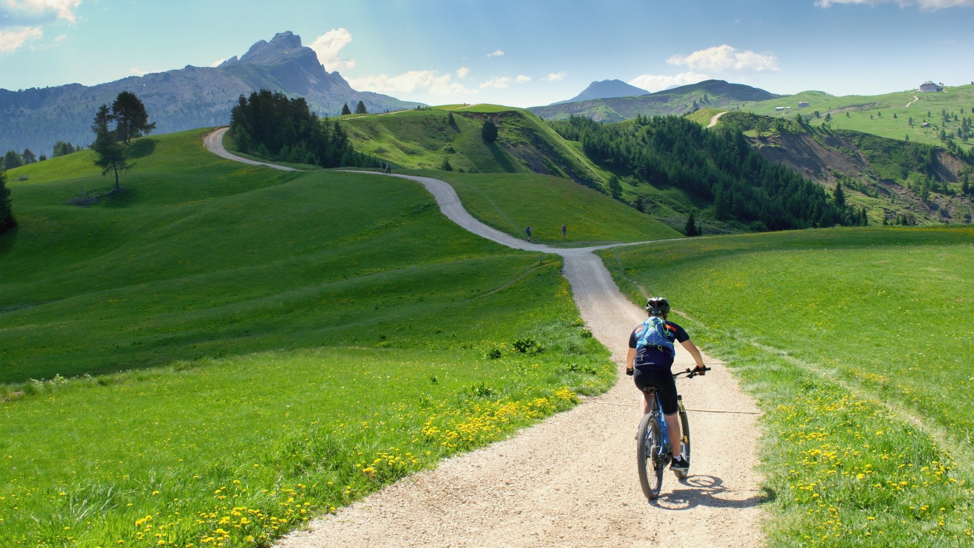 A cyclist riding along a scenic path in beautiful summer mountain scenery in the Dolomites. 