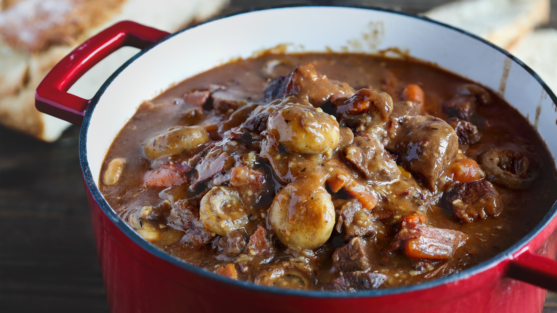 A close-up of a red pot filled with Boeuf Bourguignon. 