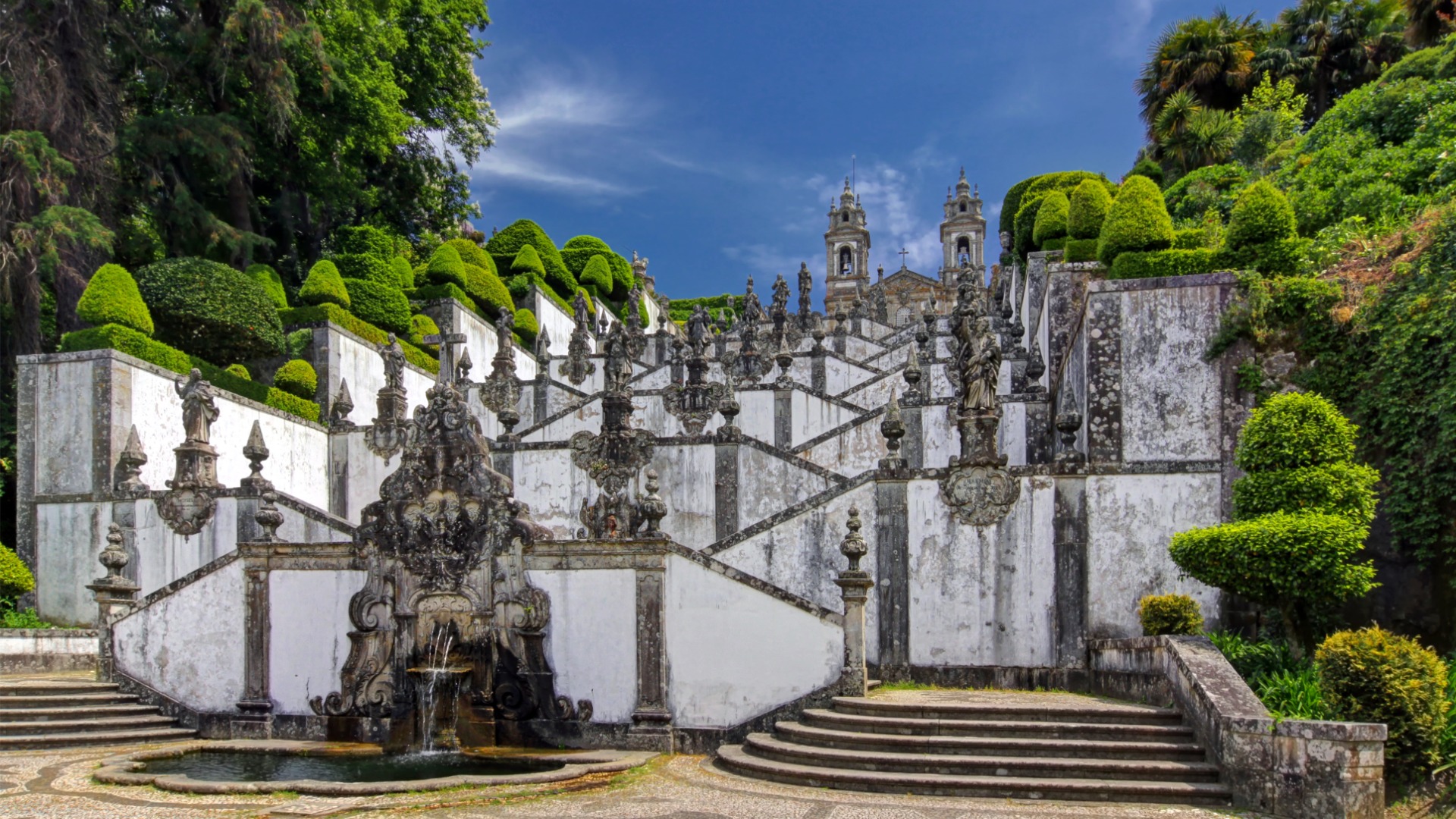 The stairs of Bom Jesus do Monte Church in Braga, North Portugal, with trees and plants on both sides.

