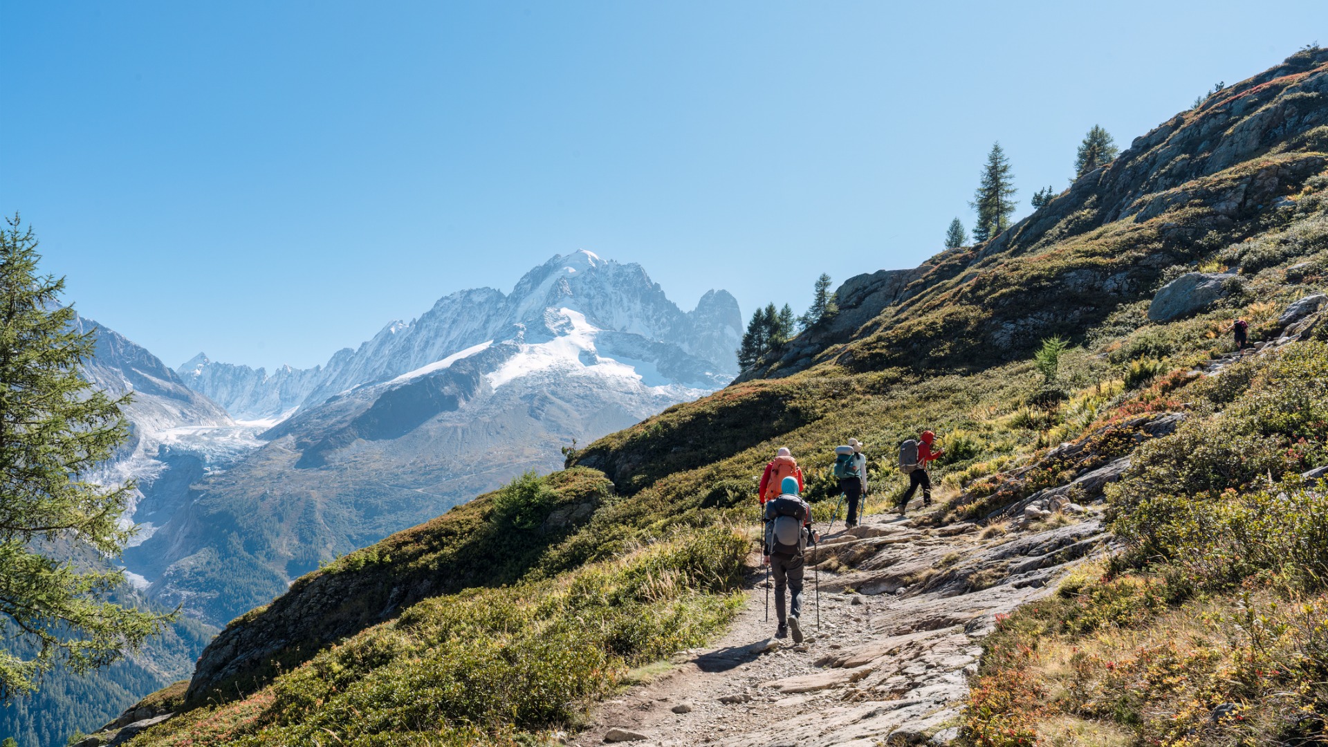 A group of hikers hiking on a summit trail to Lac Blanc amidst the French Alps on a sunny day. If you're into hiking, summer is the best time to visit France. 

