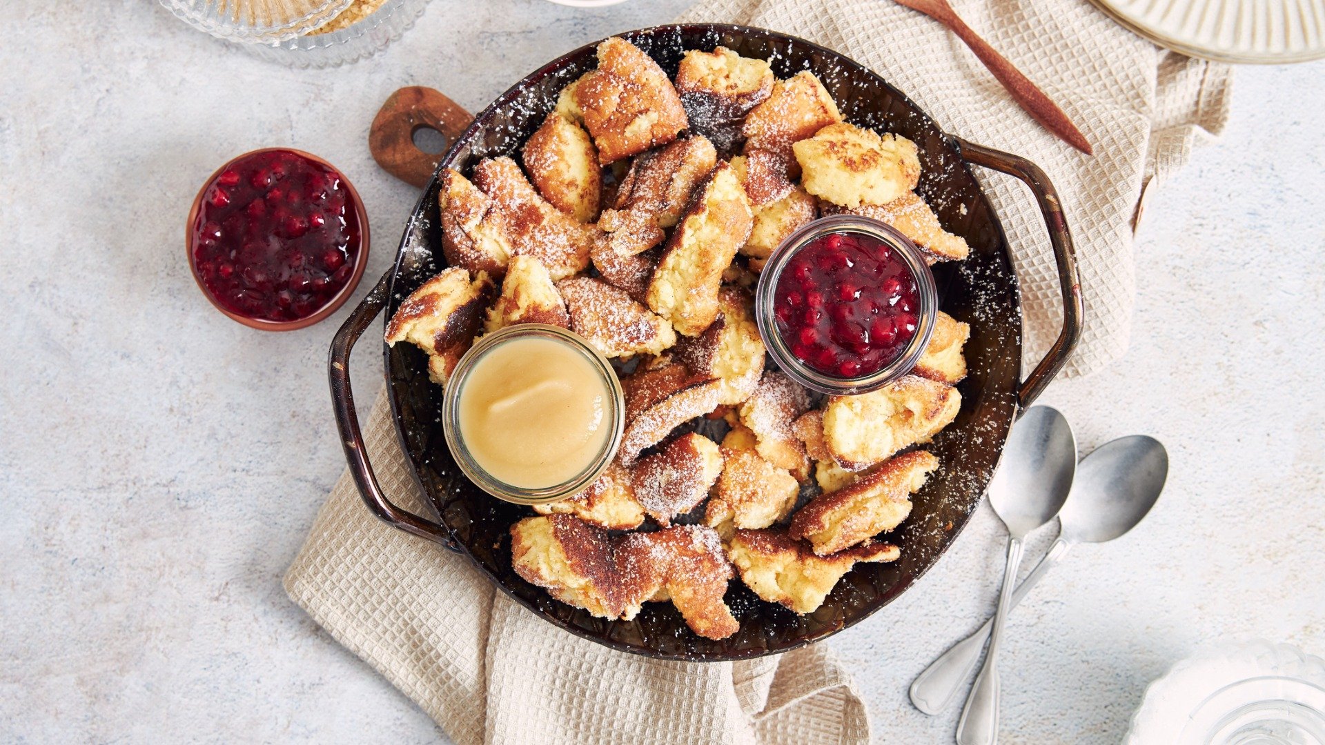 Top view of Kaiserschmarrn with torn pancakes, cranberries jam, and apple puree on a table. Kaiserschmarrn is one of the best desserts in Vienna. 