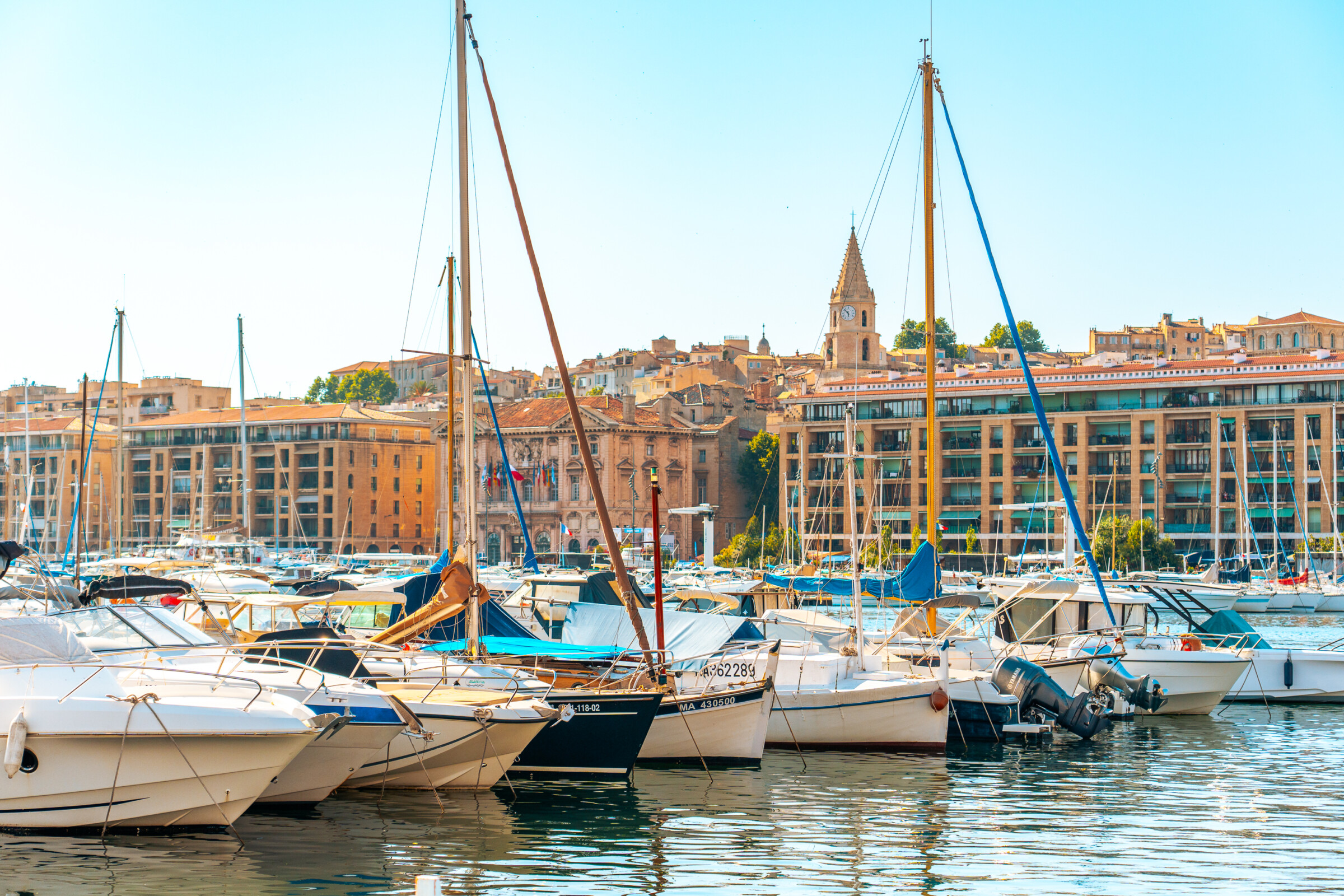 Yachts lined up in the Old Port of Marseille with buildings in the background. 