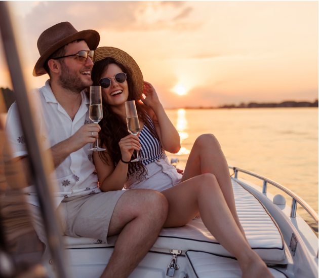 Couple drinking champagne on a sailboat at sunset