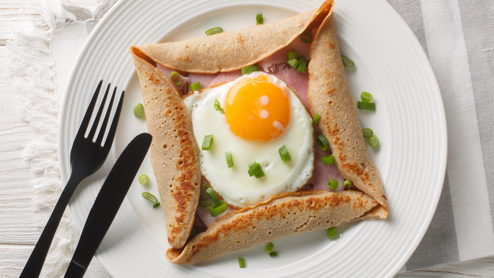 A close up of a crepe with an egg on top.