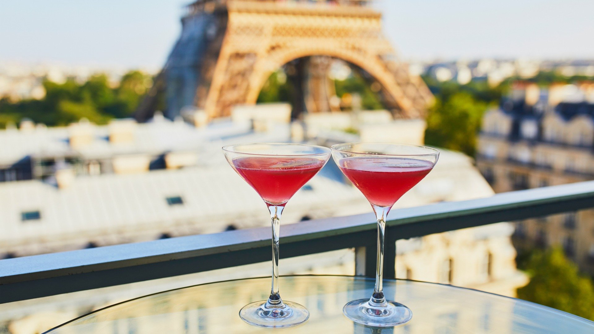 Two Cosmopolitan cocktails in traditional martini glasses with views of the Eiffel tower.