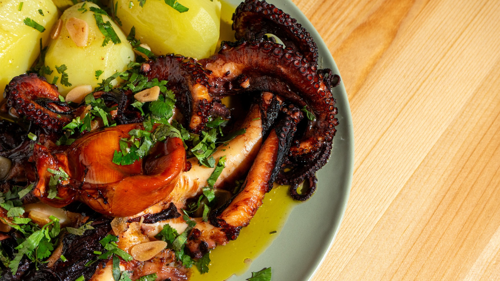 A close up of a dish with grilled octopus and boiled potatoes. 