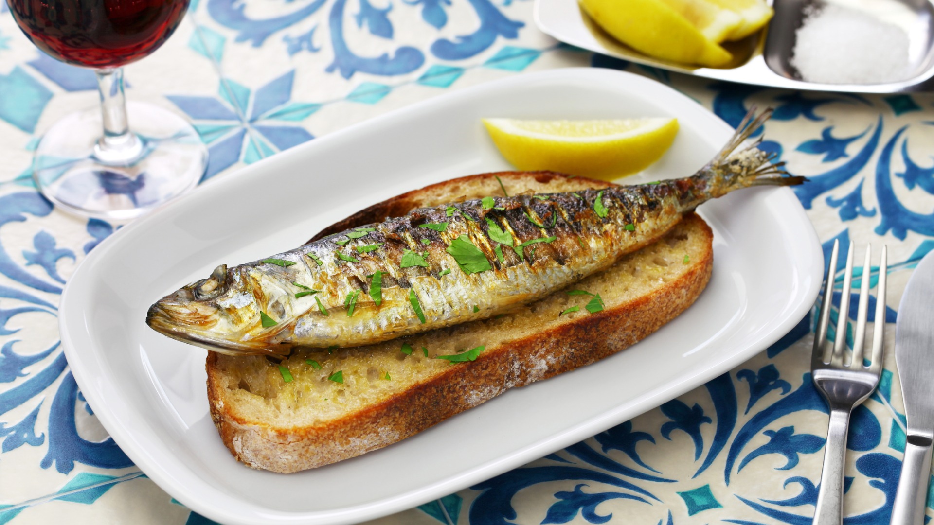 A close up of a grilled sardine on a slice of toasted bread.