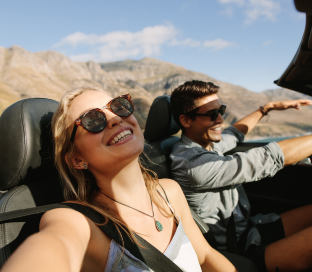 A couple on a road trip in the mountains in a convertible.