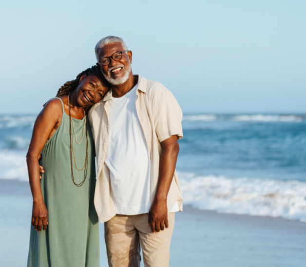 A smiling older couple on a beach.