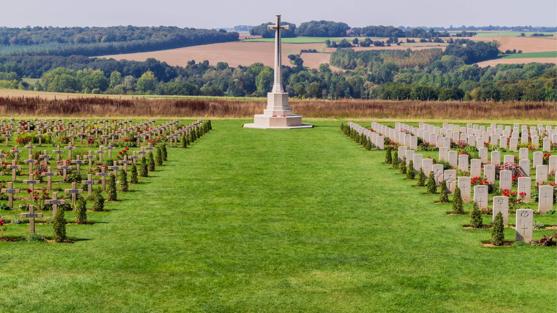 A large cross flanked by tombstones in a green field. The Thiepval Memorial is part of one of the collective UNESCO World Heritage Sites in France. 