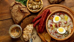 A bowl of Zurek soup, served with rye bread and mushrooms.