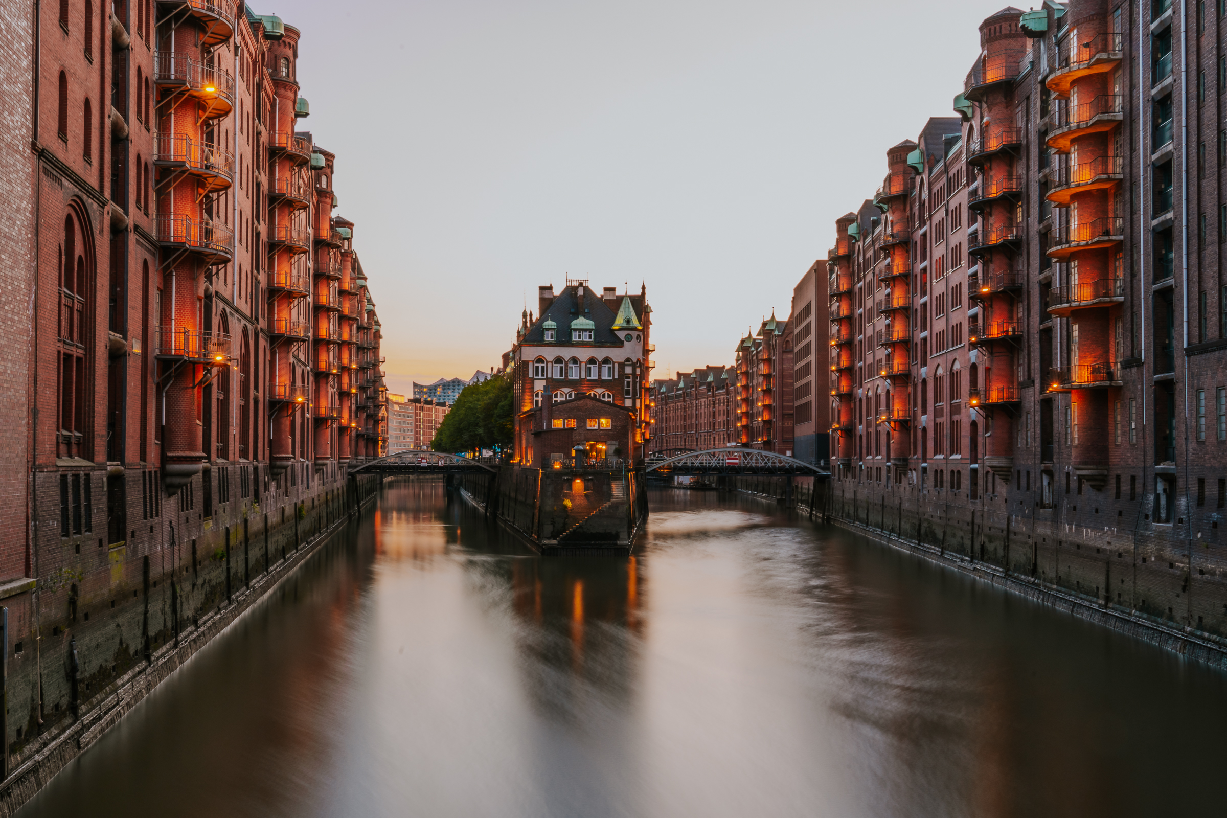 Two rows of dimly lit buildings along a river. 