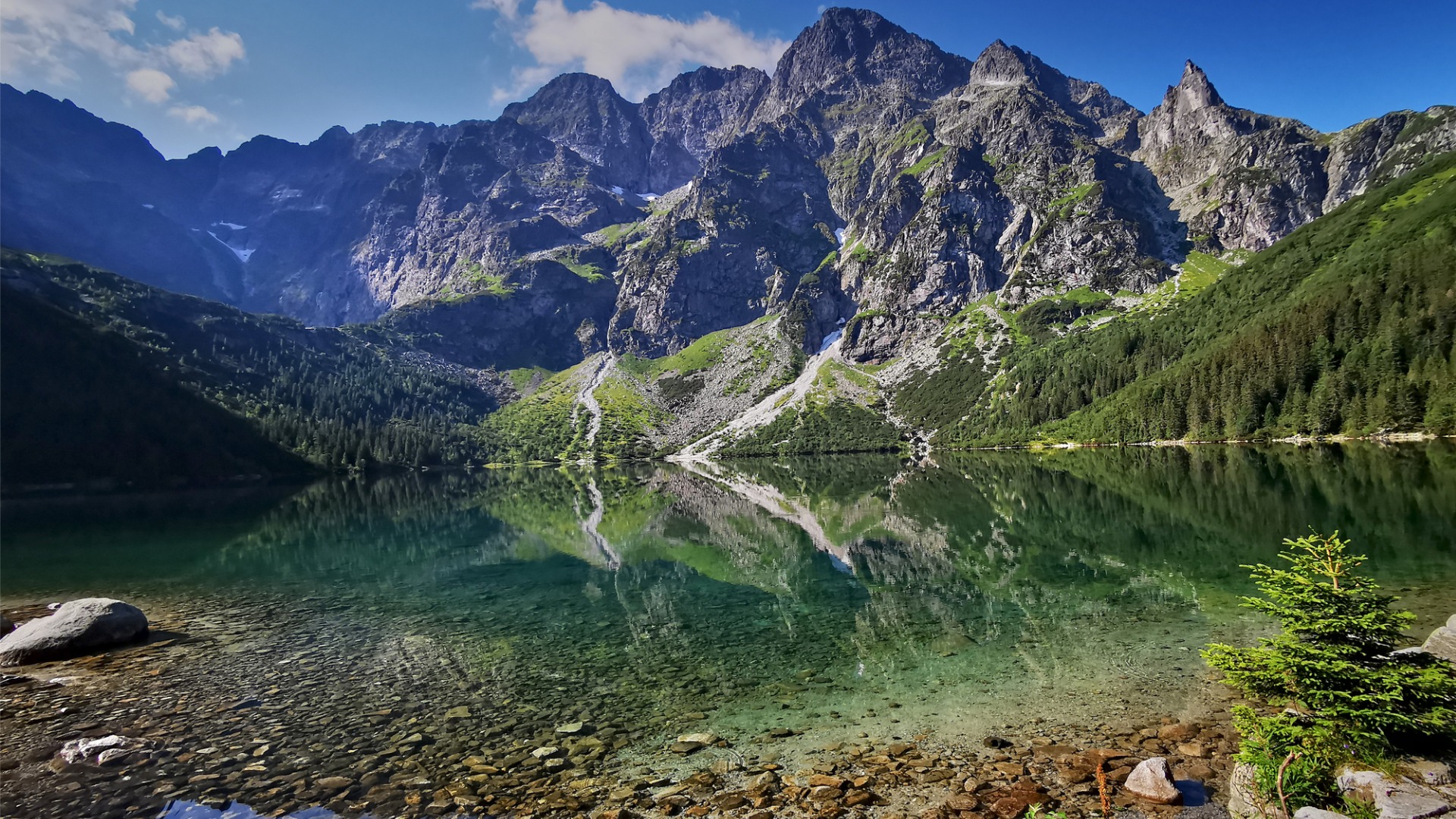 A lake with transparent waters surrounded by tall mountains. 