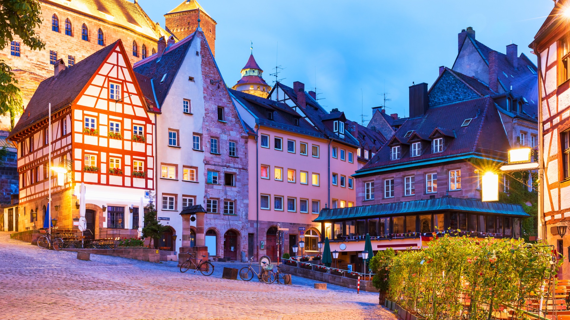 Cobbled streets lined with beautiful houses, which are dimly lit at dusk. 