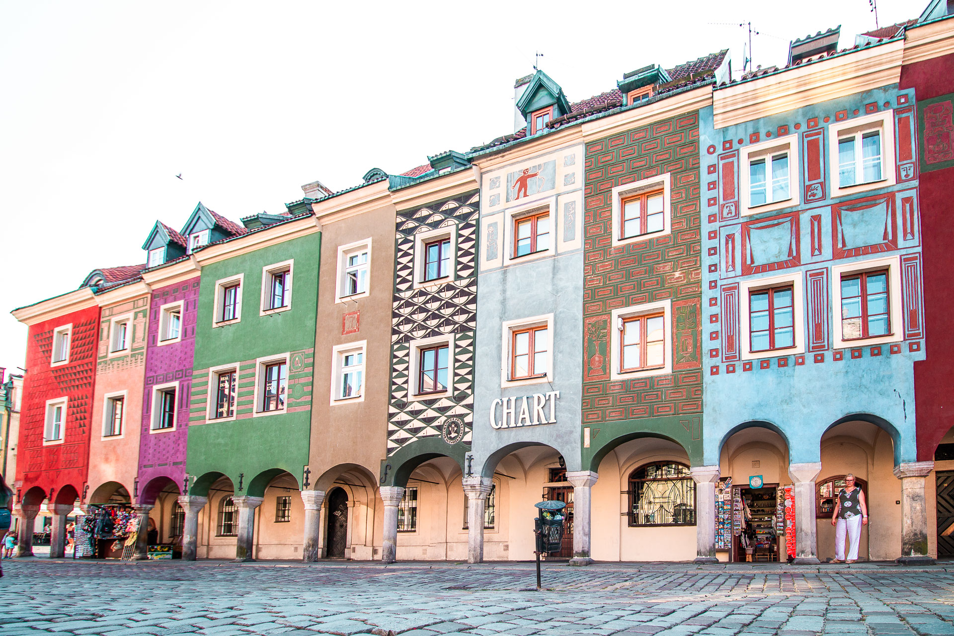 A row of colorful buildings along a cobbled street. 