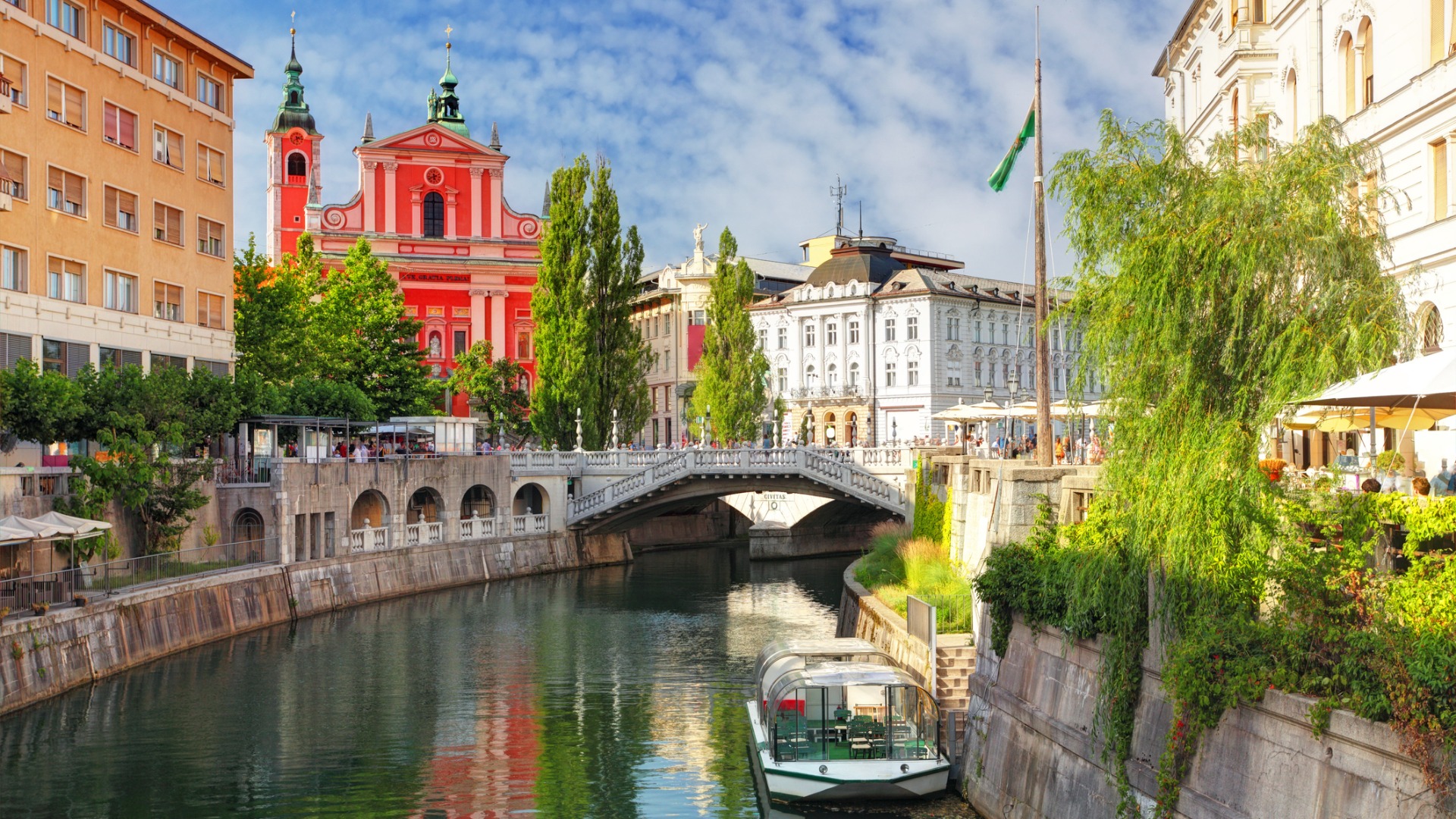 A river lined with grand buildings and a red church in the background. 