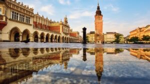 This image shows a square with magnificent buildings. There's water on the ground, and you can see the reflections of the buildings on the water.