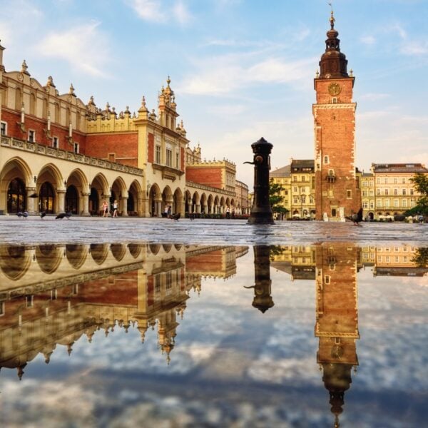 This image shows a square with magnificent buildings. There's water on the ground, and you can see the reflections of the buildings on the water.