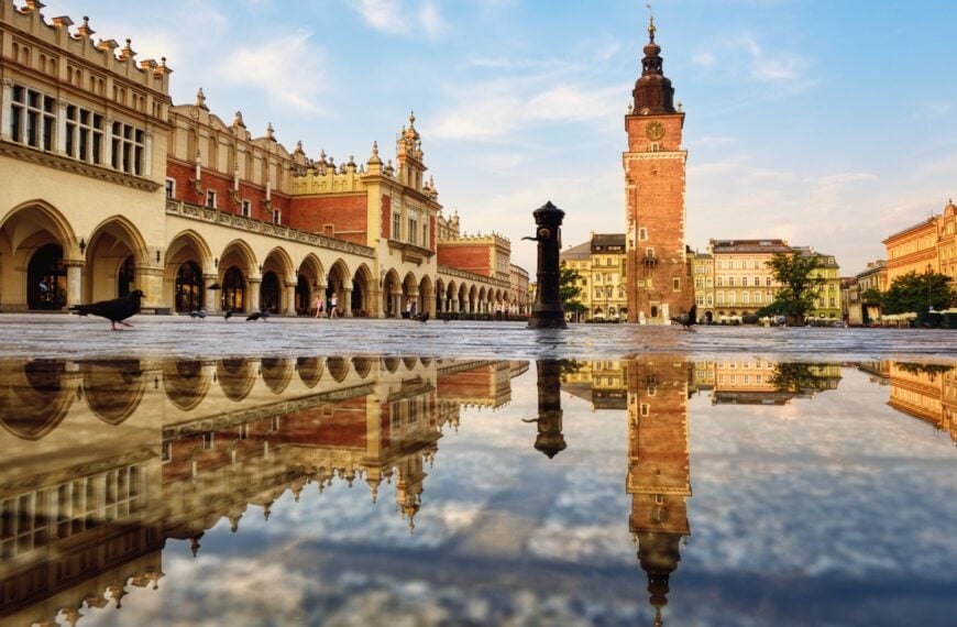 This image shows a square with magnificent buildings. There's water on the ground, and you can see the reflections of the buildings on the water.